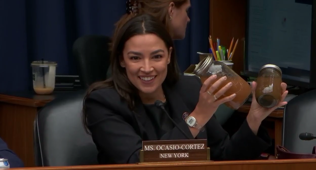 Representative Alexandria Ocasio-Cortez holds jars of discolored Georgia well water during a congressional hearing